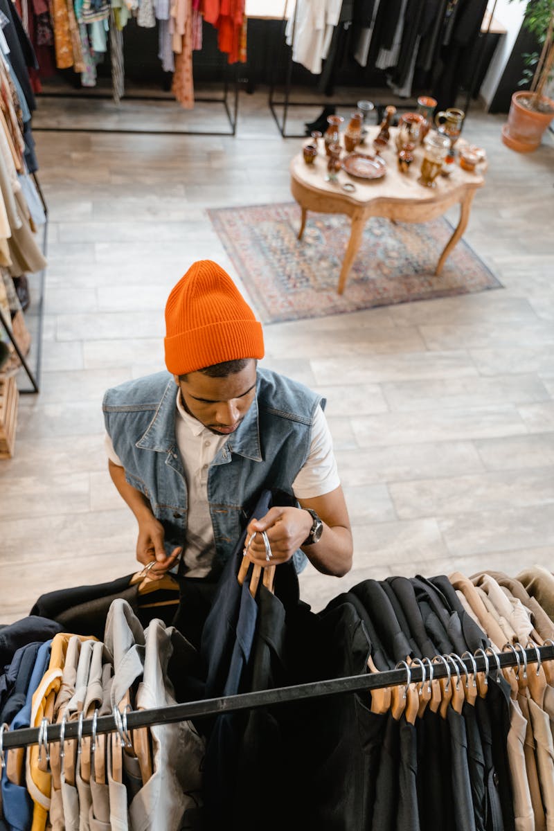 Overhead view of a man in a beanie browsing clothes in a boutique.